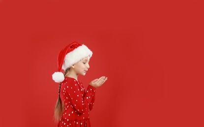 Happy little child in Santa hat on red background, space for text. Christmas celebration Image of Happy little child in Santa hat on red background, space for text. Christmas celebration