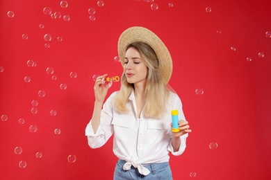 Young woman blowing soap bubbles on red background Photo of Young woman blowing soap bubbles on red background