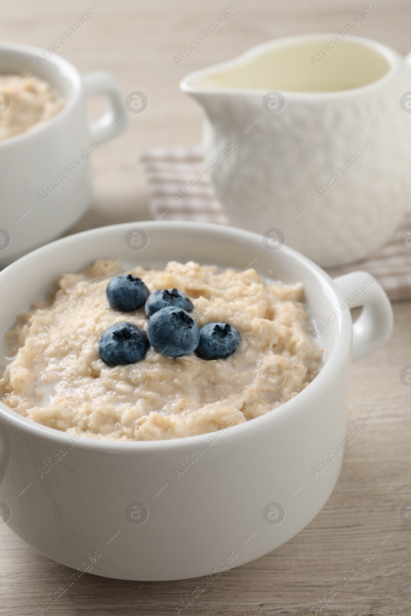 Tasty oatmeal porridge with blueberries in bowl served on wooden table Photo of Tasty oatmeal porridge with blueberries in bowl served on wooden table