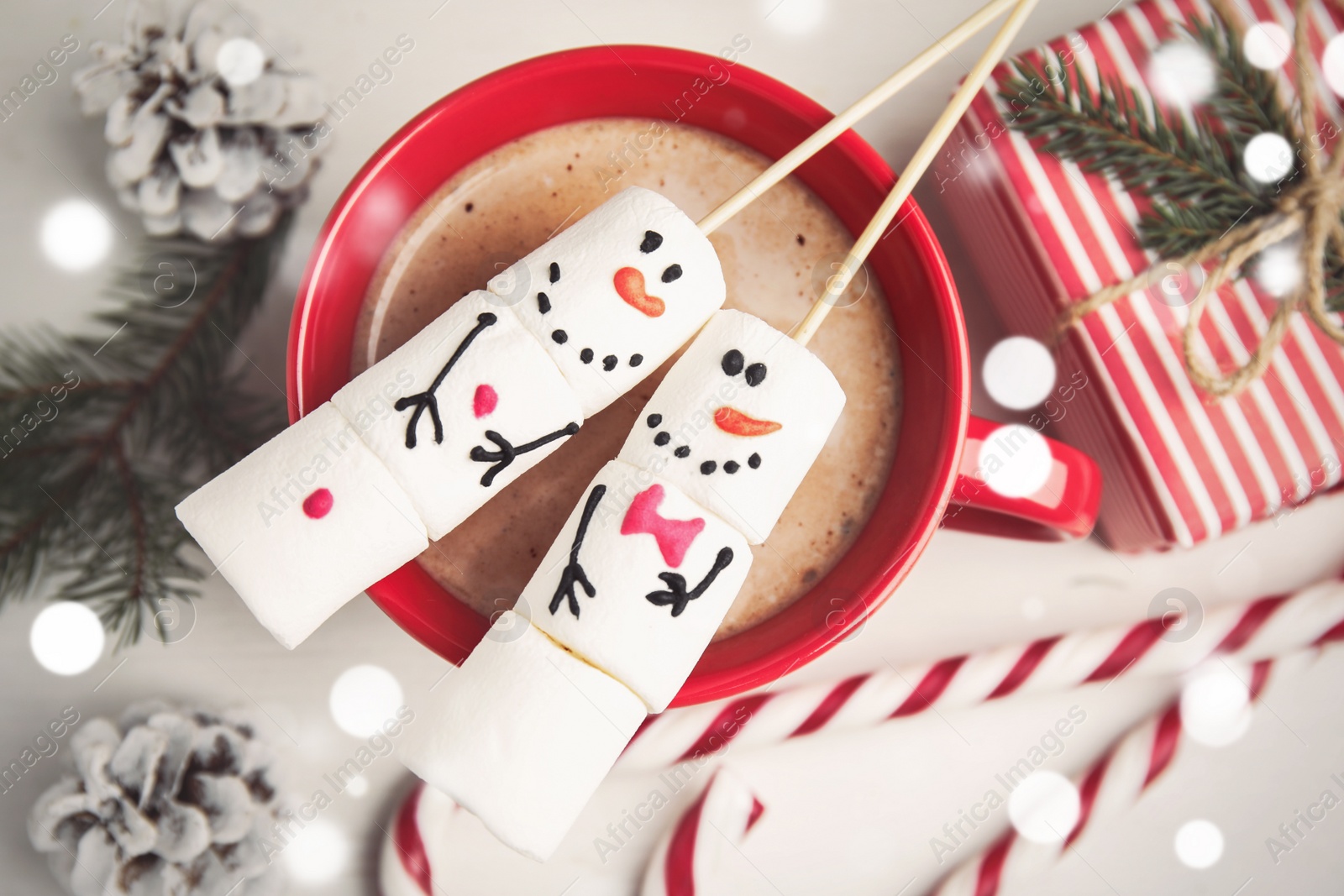 Flat lay composition with funny snowmen made of marshmallows in cup on white wooden table Photo of Flat lay composition with funny snowmen made of marshmallows in cup on white wooden table