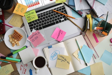 Laptop, notes and office stationery in mess on desk, top view. Overwhelmed with work Photo of Laptop, notes and office stationery in mess on desk, top view. Overwhelmed with work