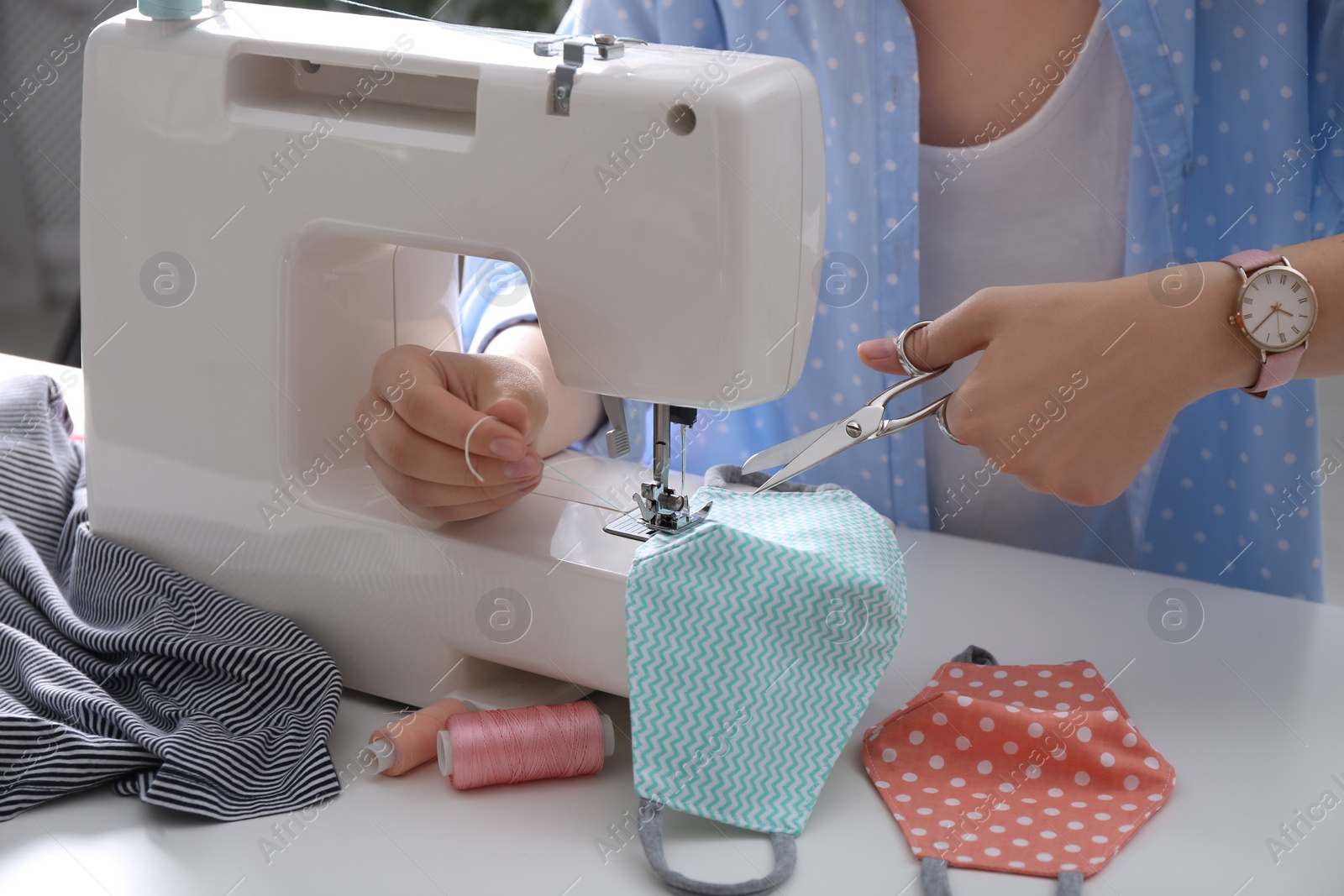Woman making cloth mask with sewing machine at white table, closeup Photo of Woman making cloth mask with sewing machine at white table, closeup