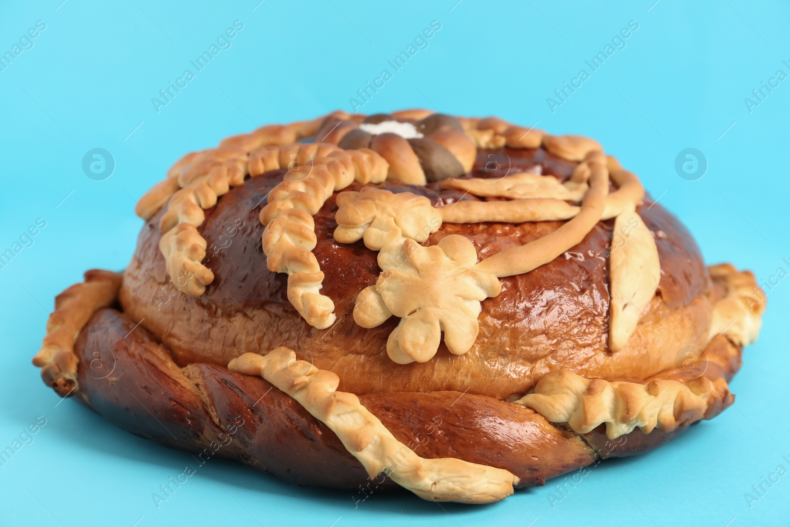 Fresh korovai on light blue background, closeup. Ukrainian bread and salt welcoming tradition Photo of Fresh korovai on light blue background, closeup. Ukrainian bread and salt welcoming tradition