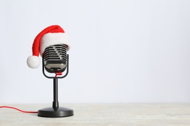 Retro microphone with Santa hat on wooden table against white background, space for text. Christmas music Photo of Retro microphone with Santa hat on wooden table against white background, space for text. Christmas music