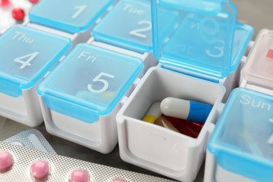 Plastic box with different pills on table, closeup Photo of Plastic box with different pills on table, closeup
