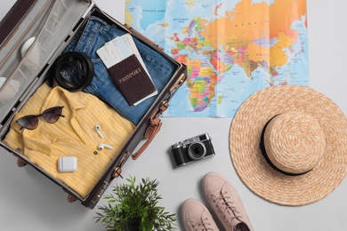 Flat lay composition with packed suitcase and travel accessories on grey background. Summer vacation Photo of Flat lay composition with packed suitcase and travel accessories on grey background. Summer vacation