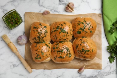 Traditional pampushka buns with garlic and herbs on white marble table, flat lay Photo of Traditional pampushka buns with garlic and herbs on white marble table, flat lay