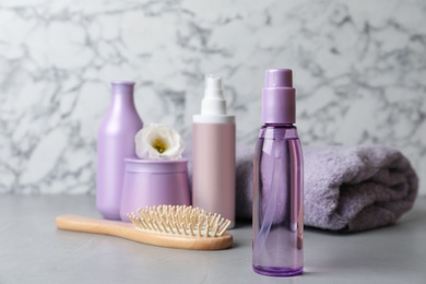 Different hair products, towel and brush on grey table. Space for text Photo of Different hair products, towel and brush on grey table. Space for text