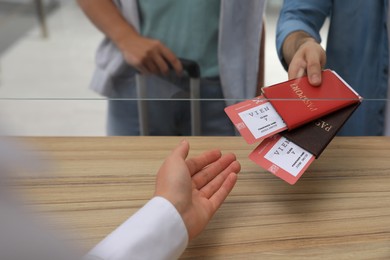 Man giving passports with tickets to agent at check-in desk in airport, closeup Photo of Man giving passports with tickets to agent at check-in desk in airport, closeup