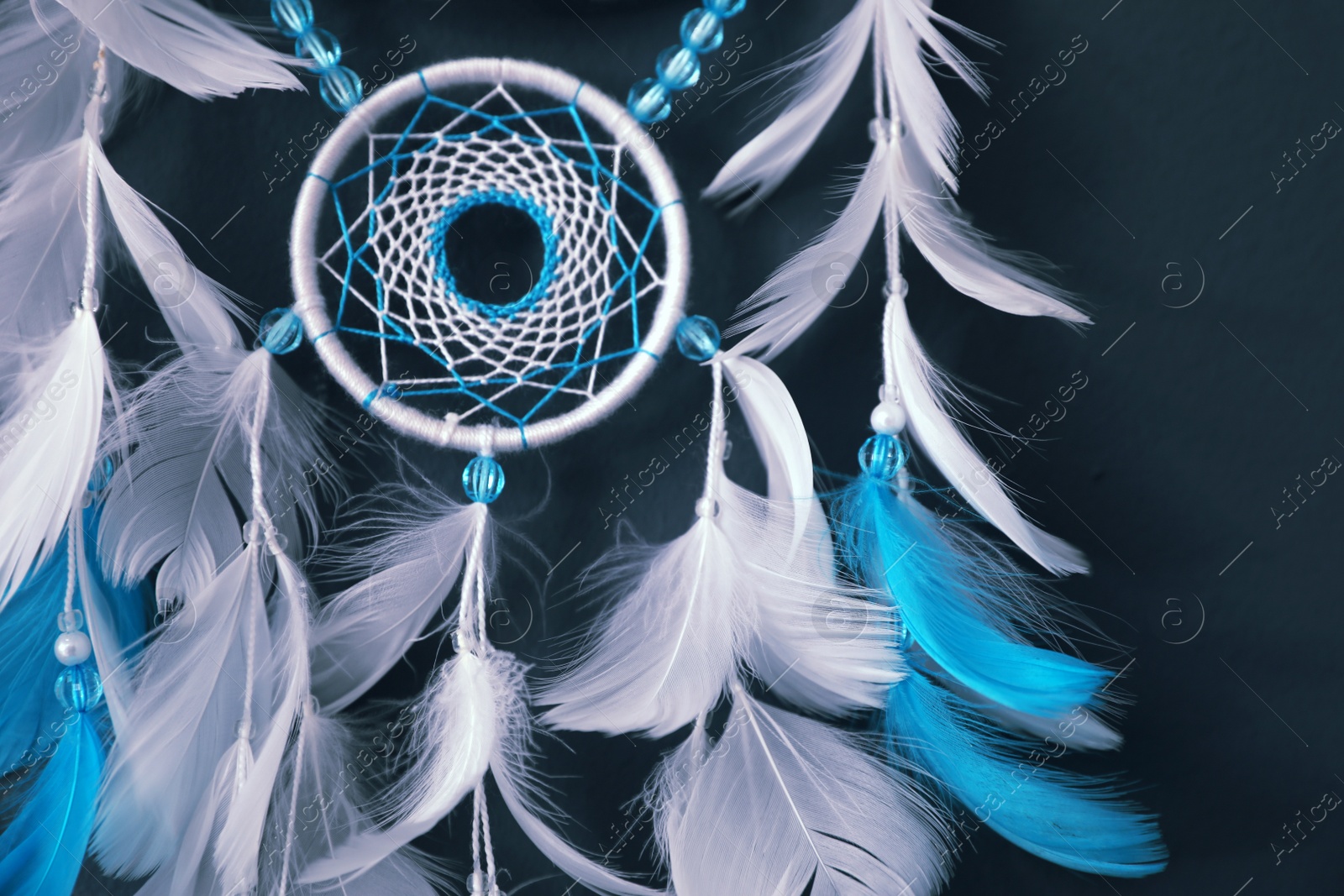 Beautiful dream catcher hanging on dark blue wall, closeup Photo of Beautiful dream catcher hanging on dark blue wall, closeup