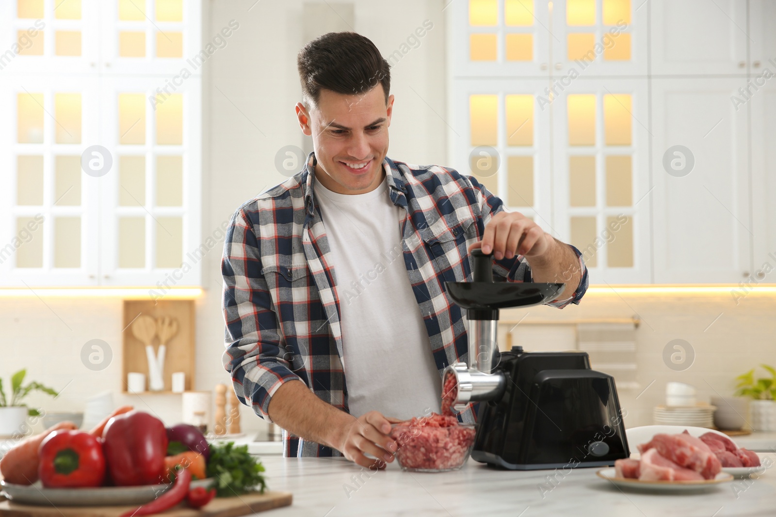 Photo of Man using modern meat grinder in kitchen