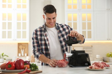 Man using modern meat grinder in kitchen Photo of Man using modern meat grinder in kitchen