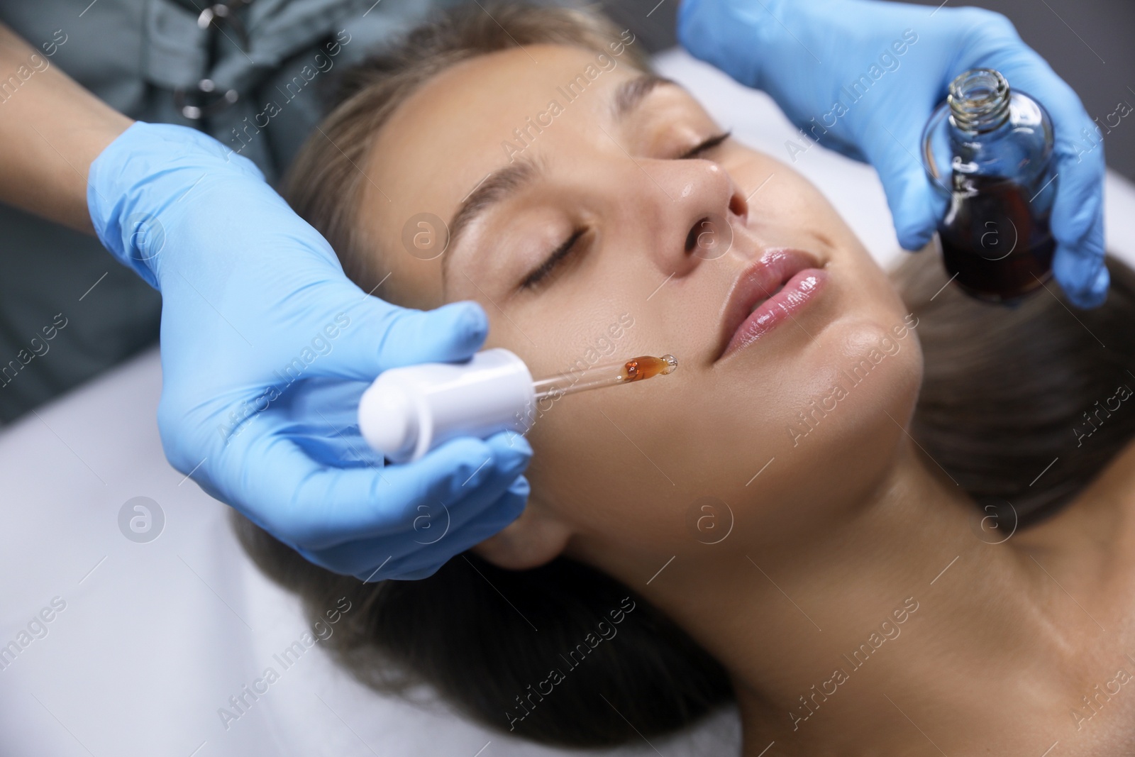 Cosmetologist applying serum on client's face in salon Photo of Cosmetologist applying serum on client's face in salon