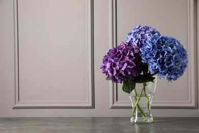 Bouquet with beautiful hortensia flowers on stone table near grey wall. Space for text Photo of Bouquet with beautiful hortensia flowers on stone table near grey wall. Space for text