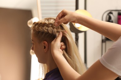 Professional stylist braiding client's hair in salon Photo of Professional stylist braiding client's hair in salon