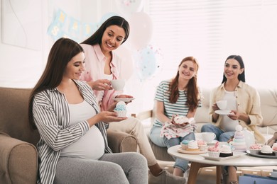Happy pregnant woman spending time with friends at baby shower party Photo of Happy pregnant woman spending time with friends at baby shower party