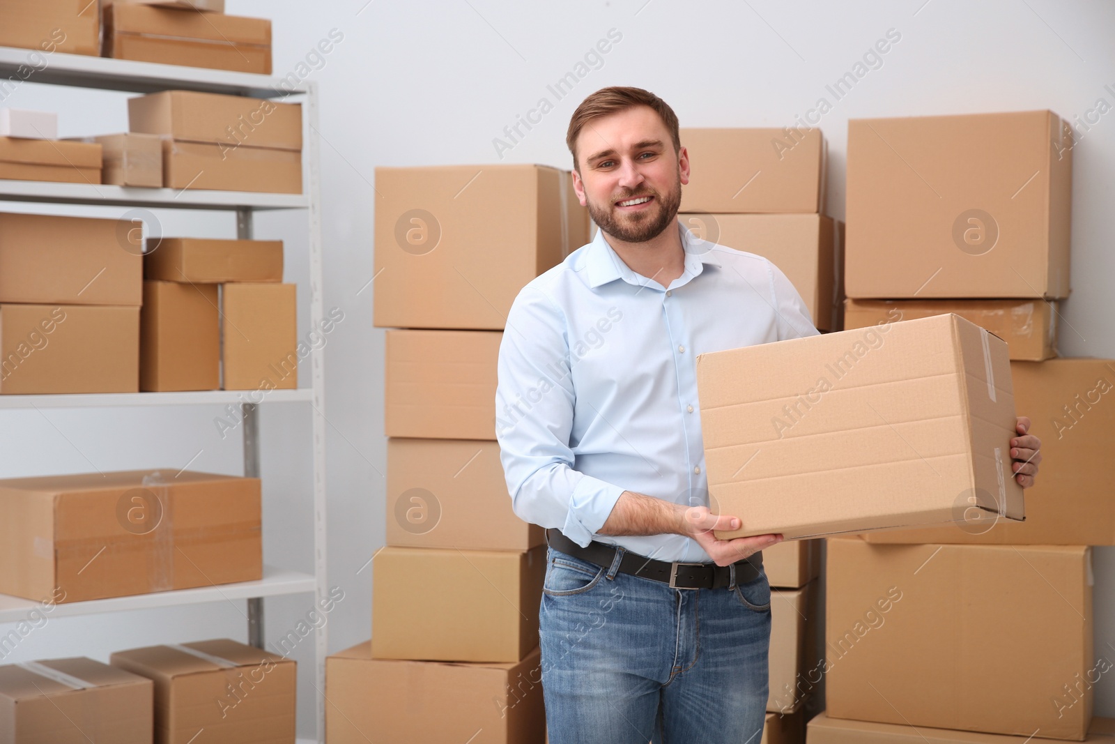 Young businessman with cardboard box at warehouse Photo of Young businessman with cardboard box at warehouse