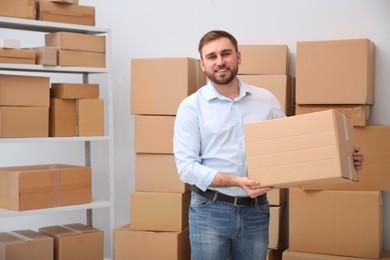 Young businessman with cardboard box at warehouse Photo of Young businessman with cardboard box at warehouse