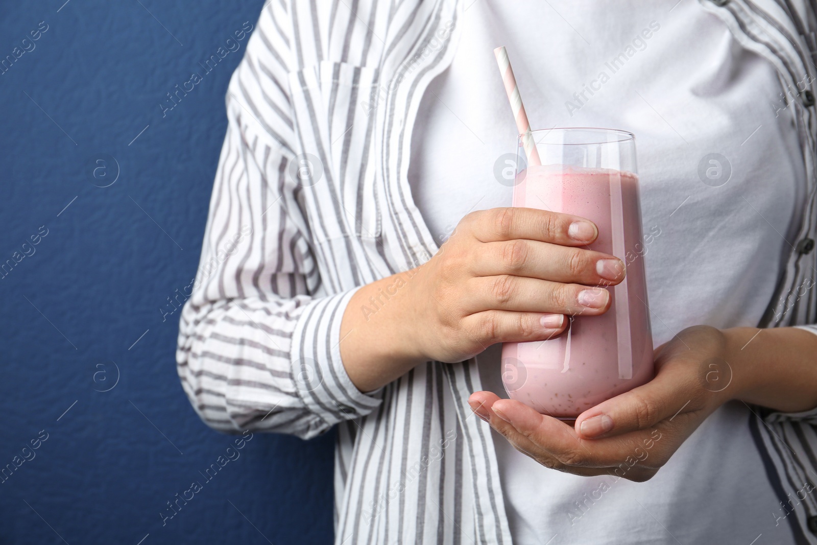 Woman with glass of tasty smoothie on blue background, closeup Image of Woman with glass of tasty smoothie on blue background, closeup