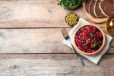 Photo of Traditional Russian salad vinaigrette served on wooden table, flat lay. Space for text