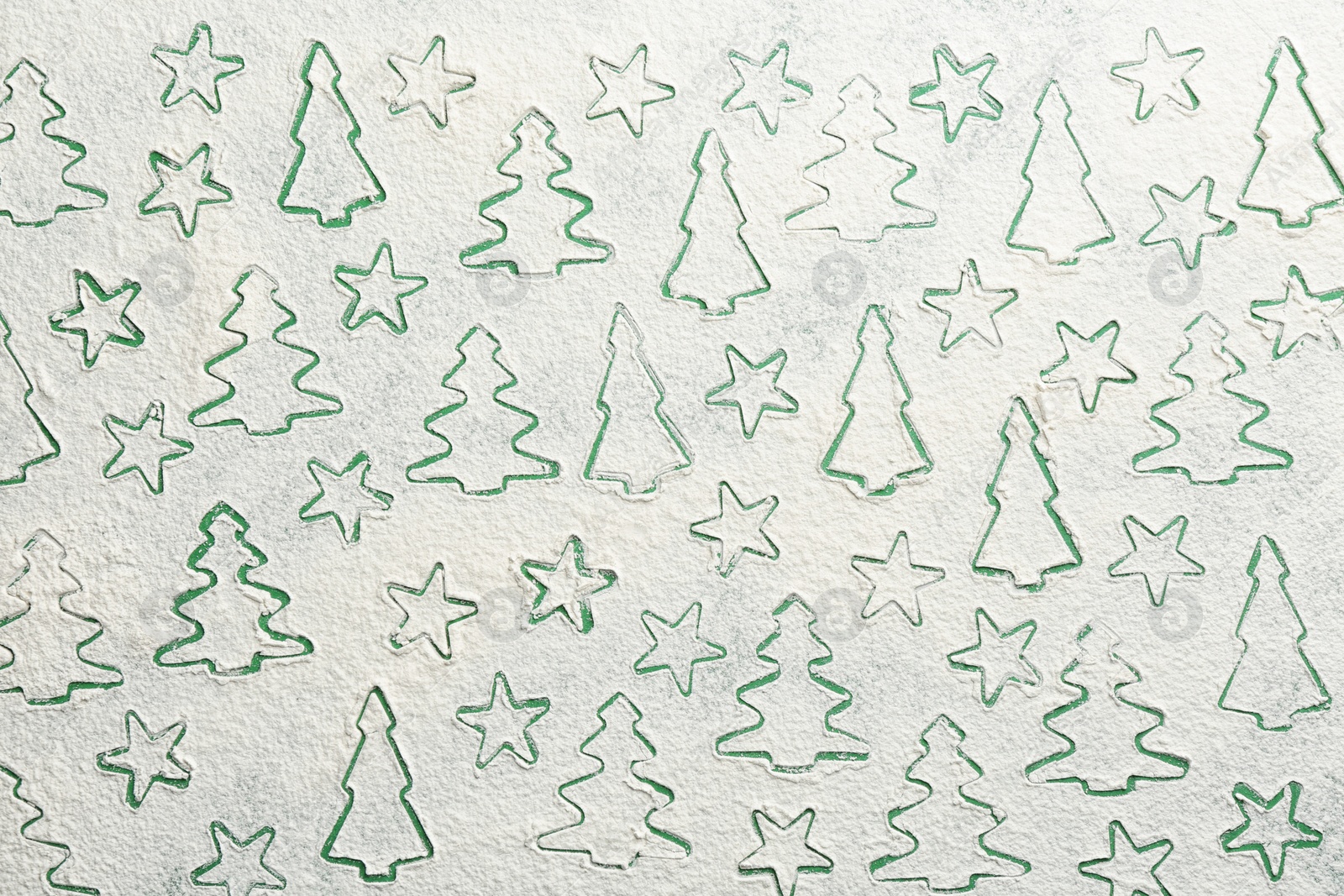 Different Christmas cookie shapes made of flour on green background, top view Photo of Different Christmas cookie shapes made of flour on green background, top view