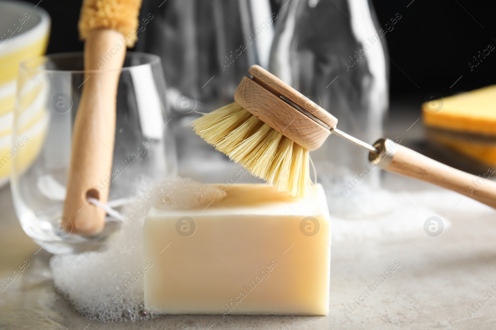 Cleaning brush and soap bar for dish washing on grey table, closeup Photo of Cleaning brush and soap bar for dish washing on grey table, closeup