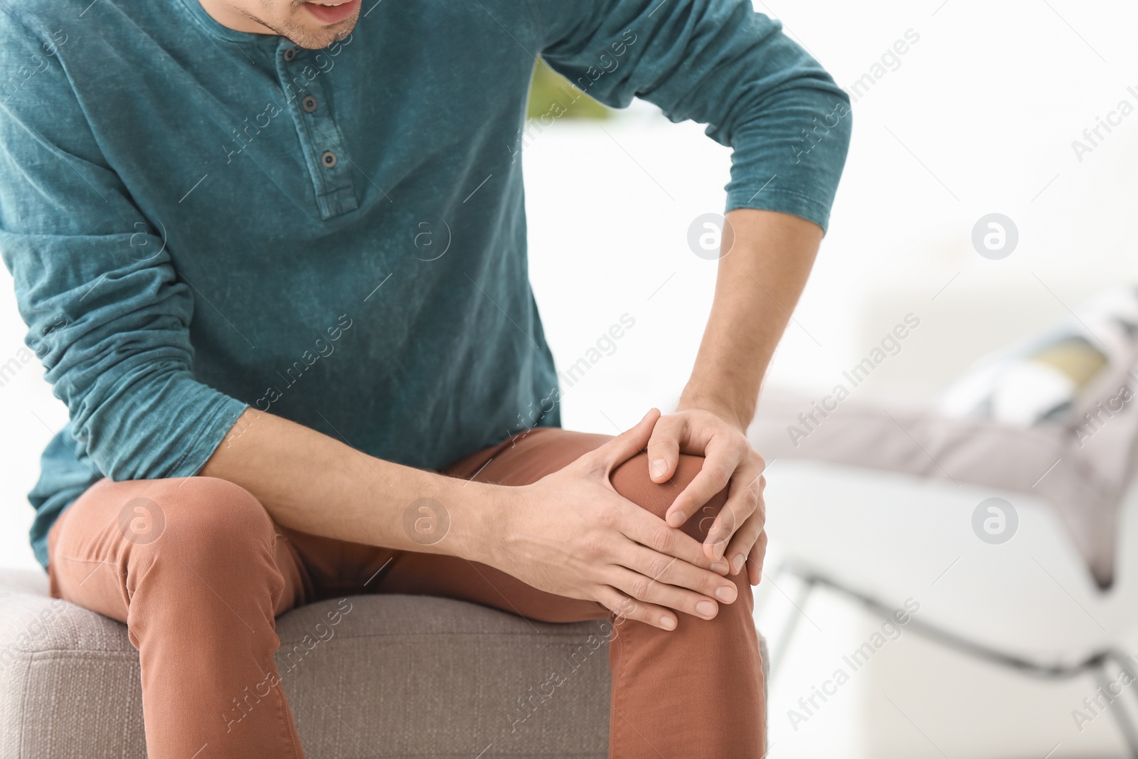 Young man suffering from knee pain at home Photo of Young man suffering from knee pain at home