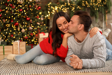 Happy young couple lying on floor in living room decorated for Christmas Photo of Happy young couple lying on floor in living room decorated for Christmas