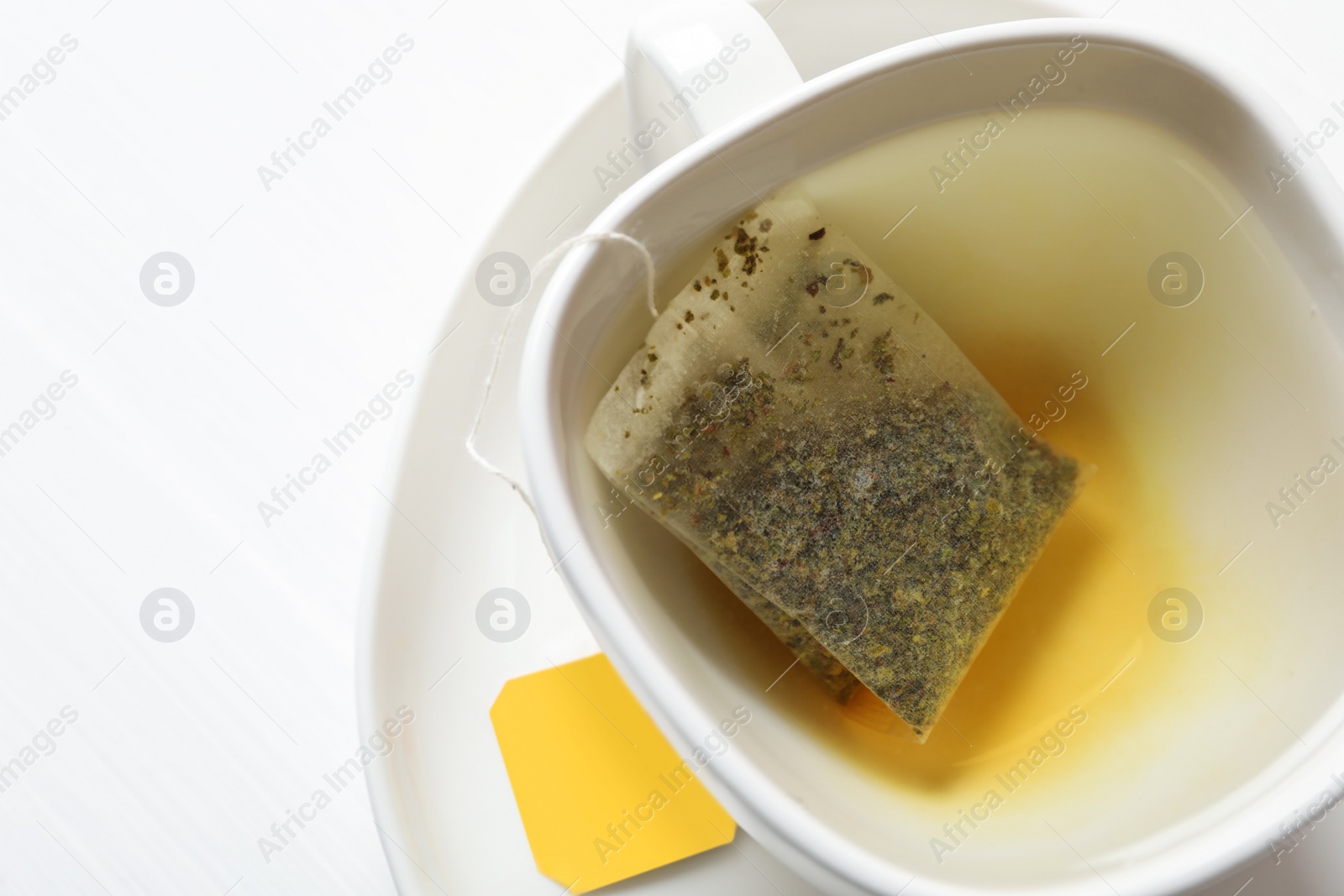 Tea bag in cup with water on white table, top view. Space for text Photo of Tea bag in cup with water on white table, top view. Space for text