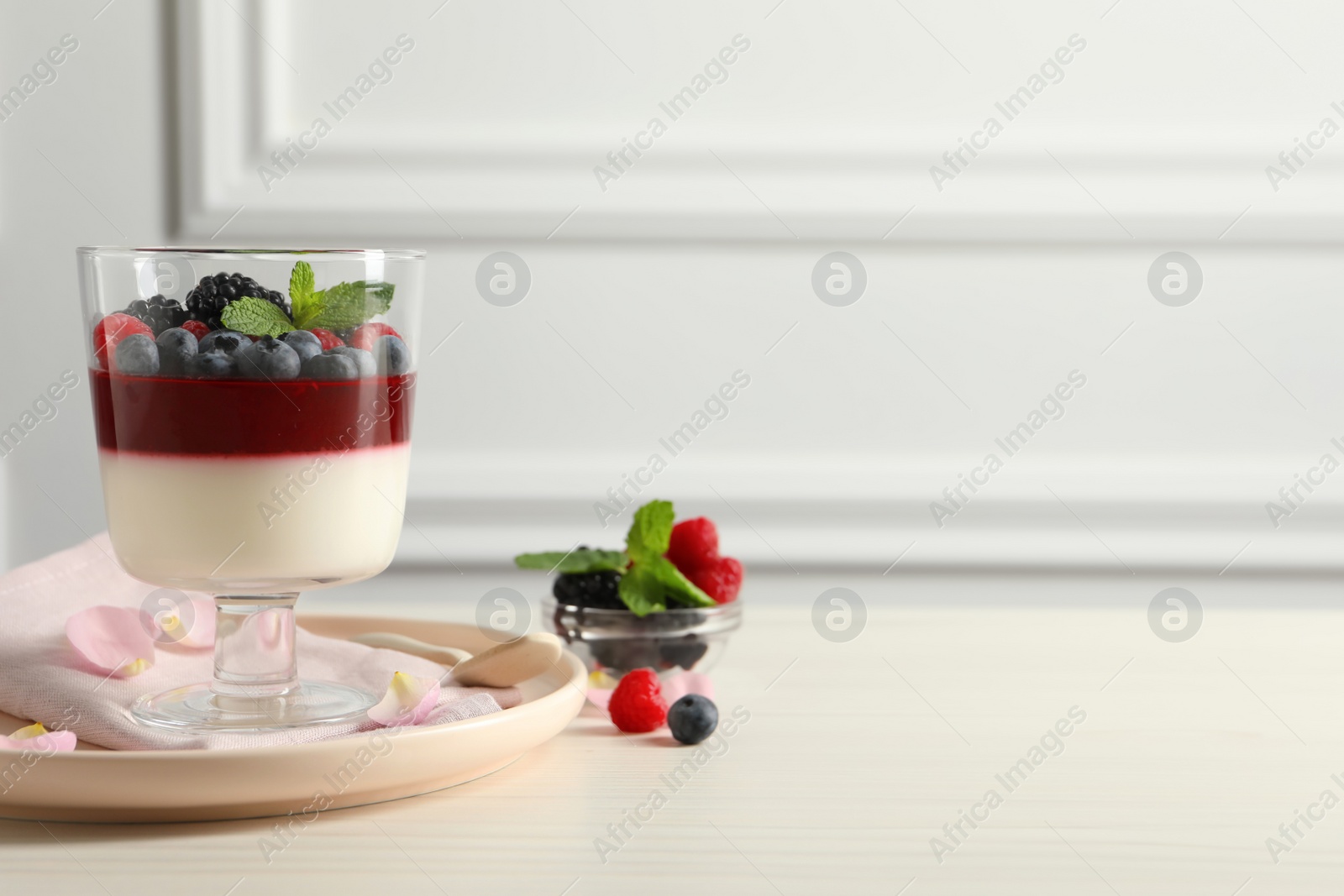 Delicious panna cotta with berries on white wooden table. Space for text Photo of Delicious panna cotta with berries on white wooden table. Space for text