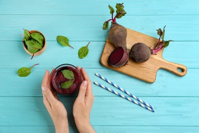 Woman with glass of delicious beet juice at blue wooden table, top view Photo of Woman with glass of delicious beet juice at blue wooden table, top view