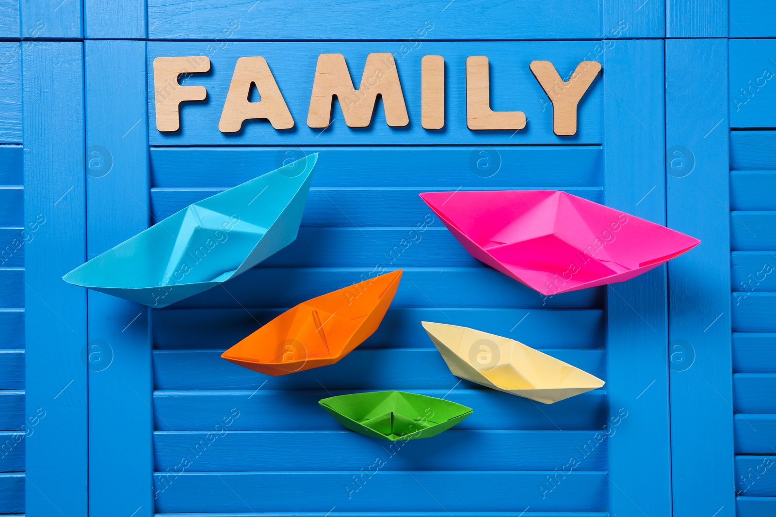 Paper ships and word Family on blue wooden background, flat lay Photo of Paper ships and word Family on blue wooden background, flat lay