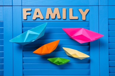 Paper ships and word Family on blue wooden background, flat lay Photo of Paper ships and word Family on blue wooden background, flat lay