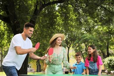 Happy family playing ping pong in park Photo of Happy family playing ping pong in park