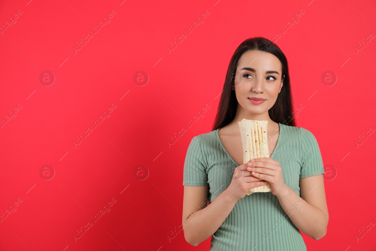 Dreamy young woman holding tasty shawarma on red background. Space for text Photo of Dreamy young woman holding tasty shawarma on red background. Space for text
