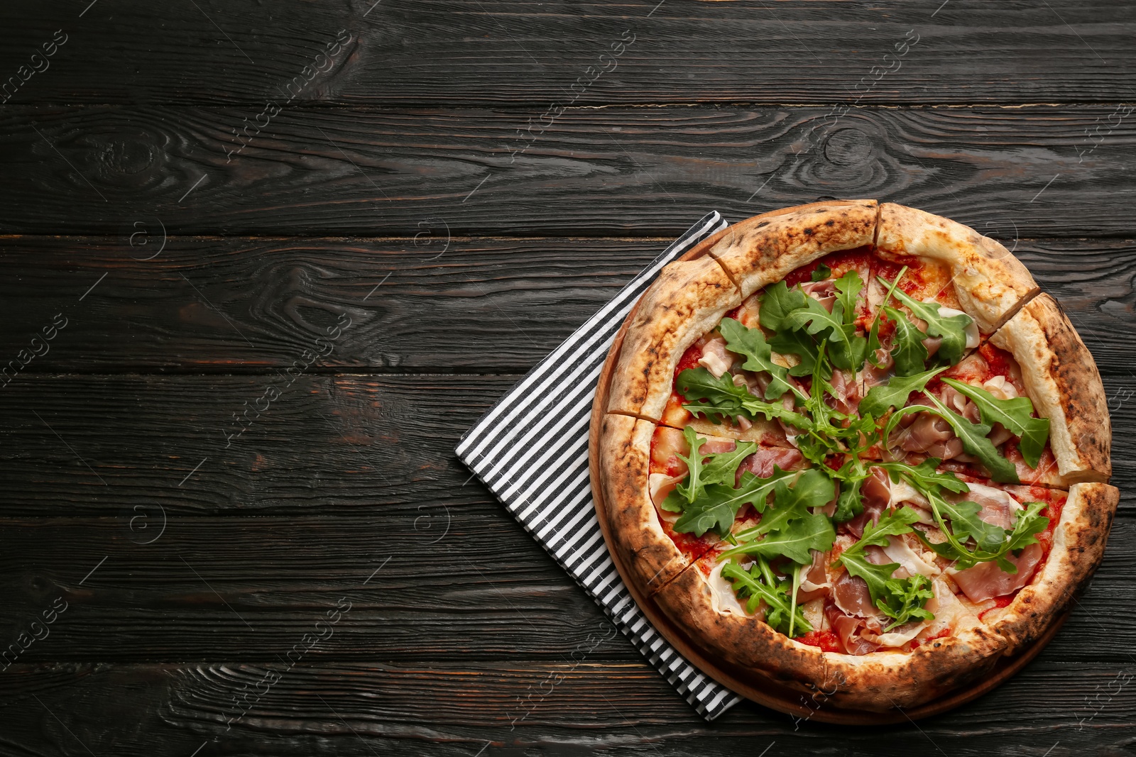 Tasty pizza with meat and arugula on black wooden table, top view. Space for text Photo of Tasty pizza with meat and arugula on black wooden table, top view. Space for text