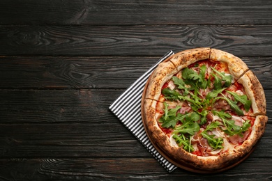 Tasty pizza with meat and arugula on black wooden table, top view. Space for text Photo of Tasty pizza with meat and arugula on black wooden table, top view. Space for text