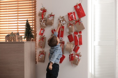 Cute little boy taking gift from Advent calendar at home. Christmas tradition Photo of Cute little boy taking gift from Advent calendar at home. Christmas tradition