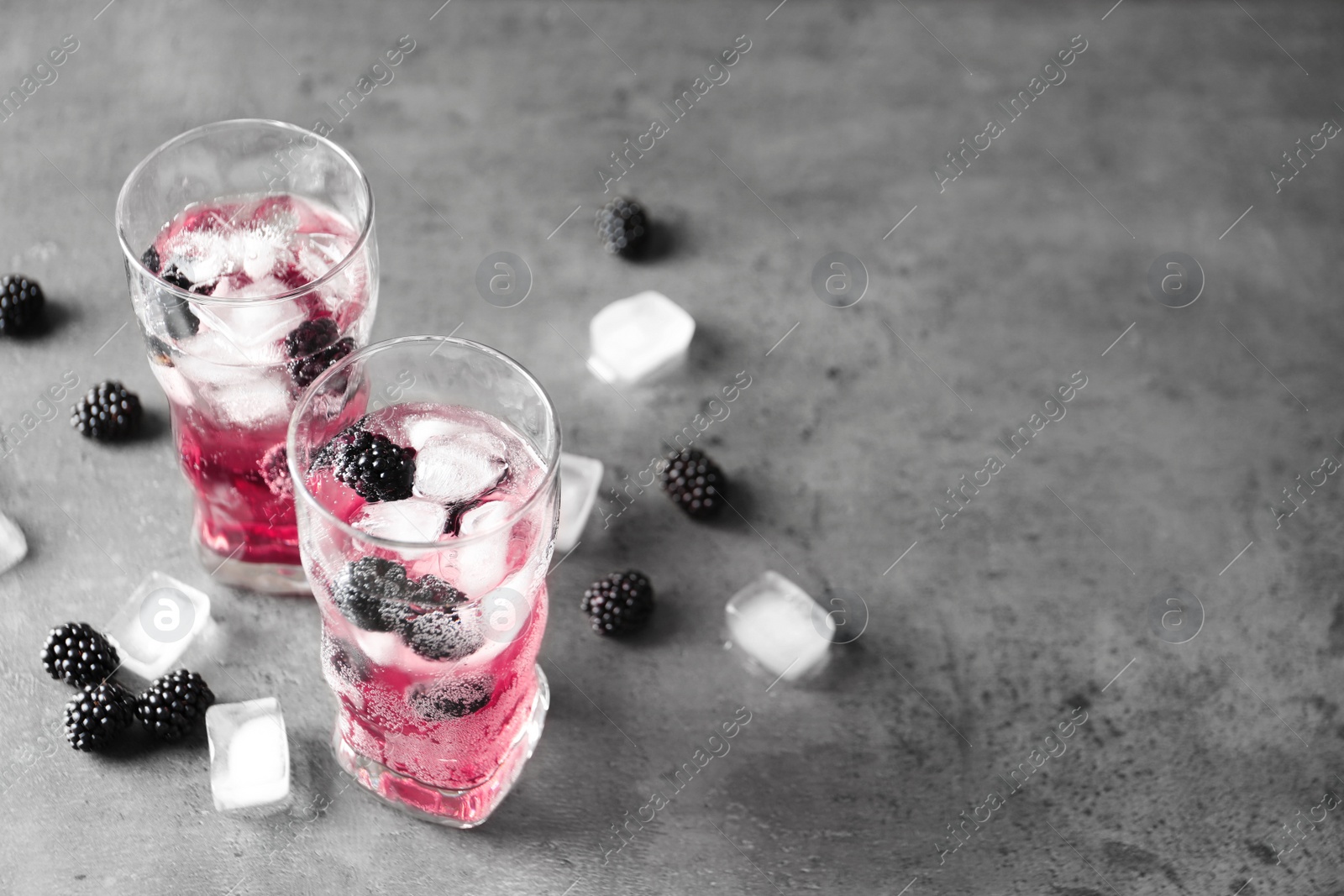 Refreshing blackberry drink with ice on grey table. Space for text Image of Refreshing blackberry drink with ice on grey table. Space for text