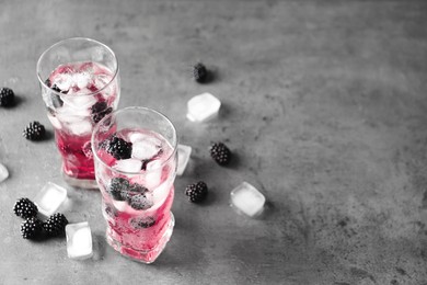 Refreshing blackberry drink with ice on grey table. Space for text Image of Refreshing blackberry drink with ice on grey table. Space for text