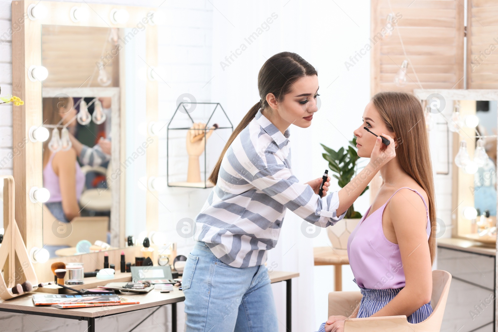 Professional visage artist applying makeup on woman's face in salon Photo of Professional visage artist applying makeup on woman's face in salon
