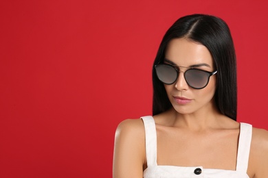 Beautiful woman wearing sunglasses on red background. Space for text Photo of Beautiful woman wearing sunglasses on red background. Space for text