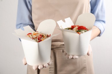 Chef holding boxes of vegetarian wok noodles on light background, closeup Photo of Chef holding boxes of vegetarian wok noodles on light background, closeup