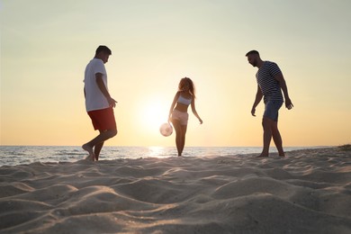 Friends playing football on beach at sunset Photo of Friends playing football on beach at sunset