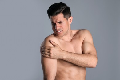 Man suffering from shoulder pain on grey background Photo of Man suffering from shoulder pain on grey background