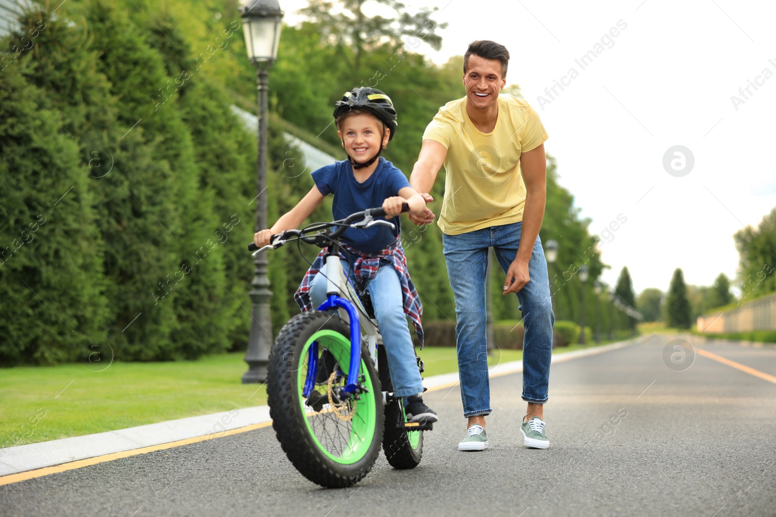 Dad teaching son to ride bicycle outdoors Image of Dad teaching son to ride bicycle outdoors