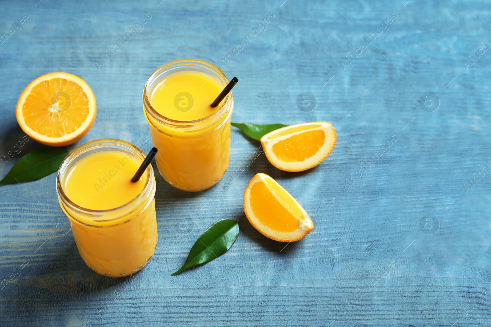 Jars of orange juice and fresh fruits on table Photo of Jars of orange juice and fresh fruits on table