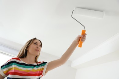 Young woman painting ceiling with white dye indoors Photo of Young woman painting ceiling with white dye indoors