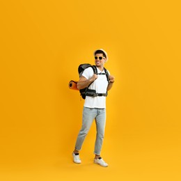 Male tourist with travel backpack on yellow background Photo of Male tourist with travel backpack on yellow background