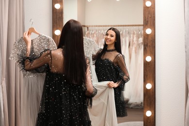 Woman choosing dress in rental clothing salon Photo of Woman choosing dress in rental clothing salon